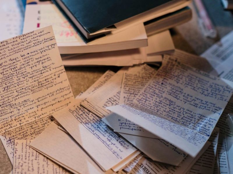 Scattered handwritten notes and books on a desk, perfect for study or research themes.